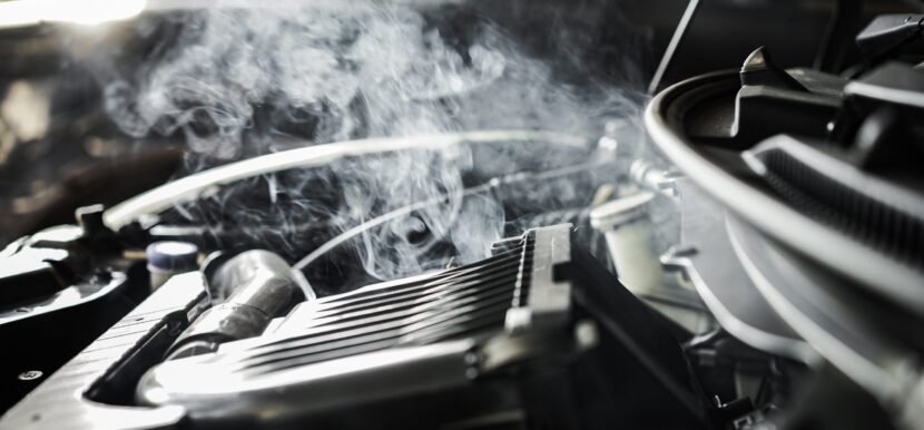 Motor de un coche sobrecalentado con vapor y medidor de temperatura